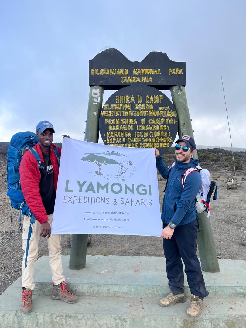 Guide and climber with Lyamongi banner at Shira II Camp