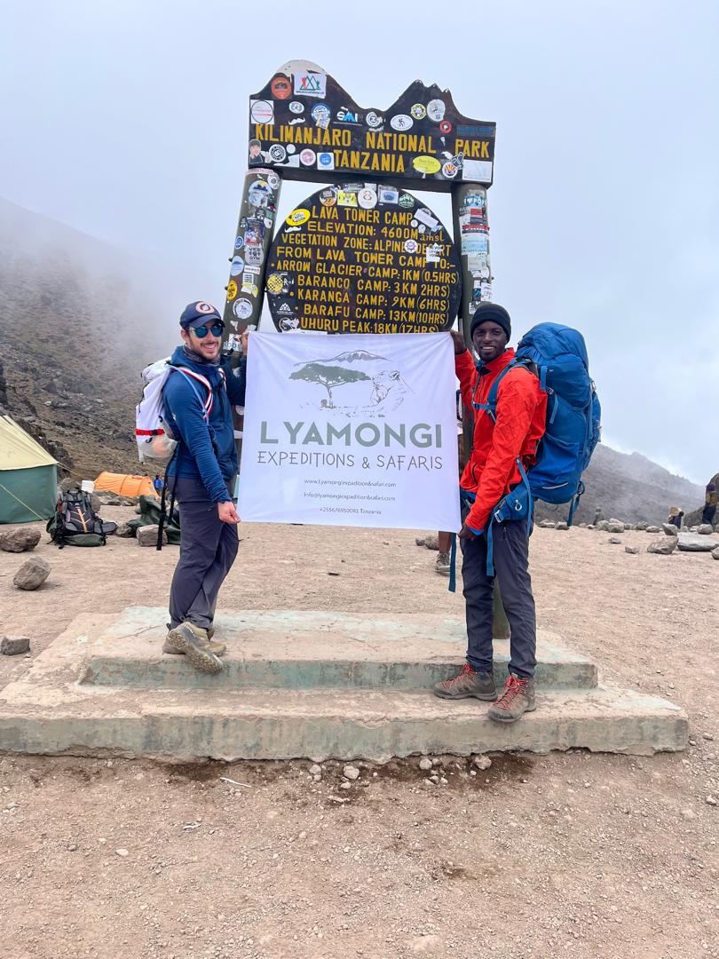 Guide and climber with Lyamongi banner at Lava Tower Camp