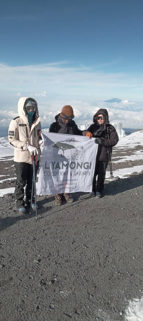 Climbers and guide with Lyamongi banner near the summit glaciers